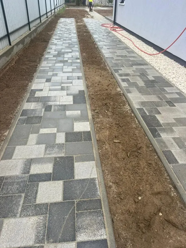 Két párhuzamos, szegéllyel lezárt kombi térkő sáv családi ház telkén