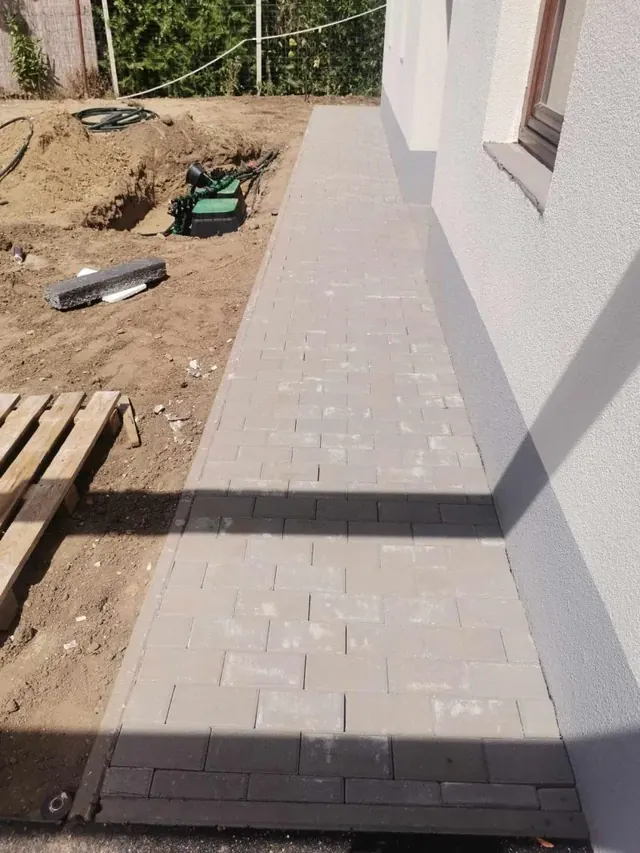 Téglakő járda a ház mentén sötét keretező sorral